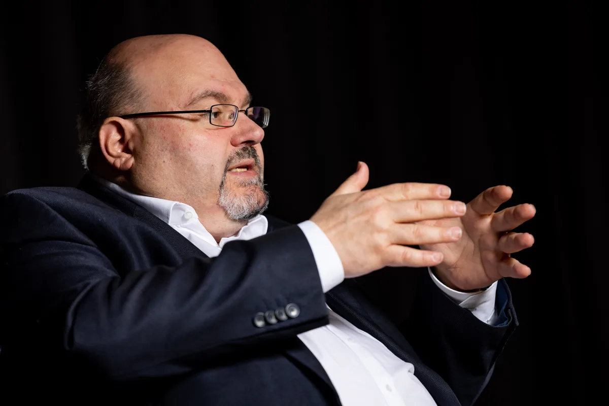 Ein Mann mit Brille diskutiert mit seinen Händen.